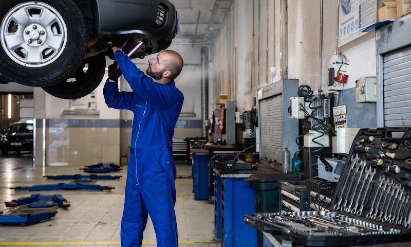 A Man in Blue Suit Checking a Car