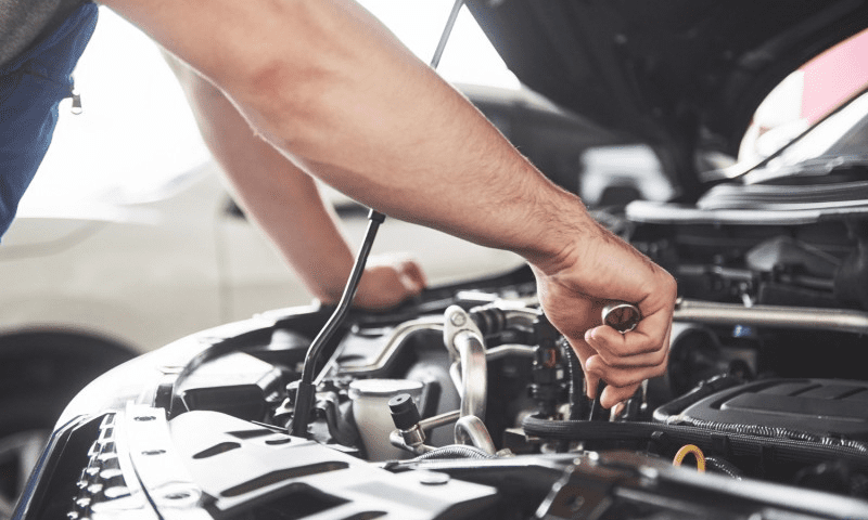 Close up hands of an unrecognizable mechanic doing car service and maintenance.